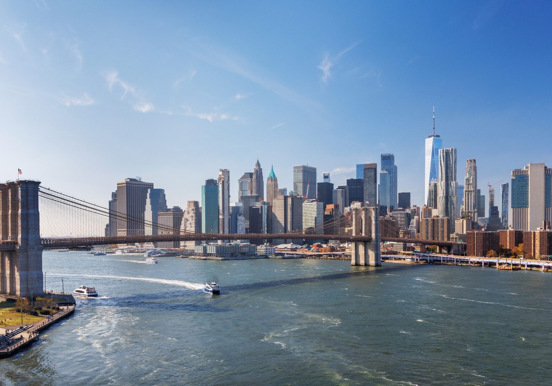 Iconic view of Brooklyn Bridge with Manhattan skyscrapers in the background, captured from Dumbo, showcasing urban elegance under a radiant sky